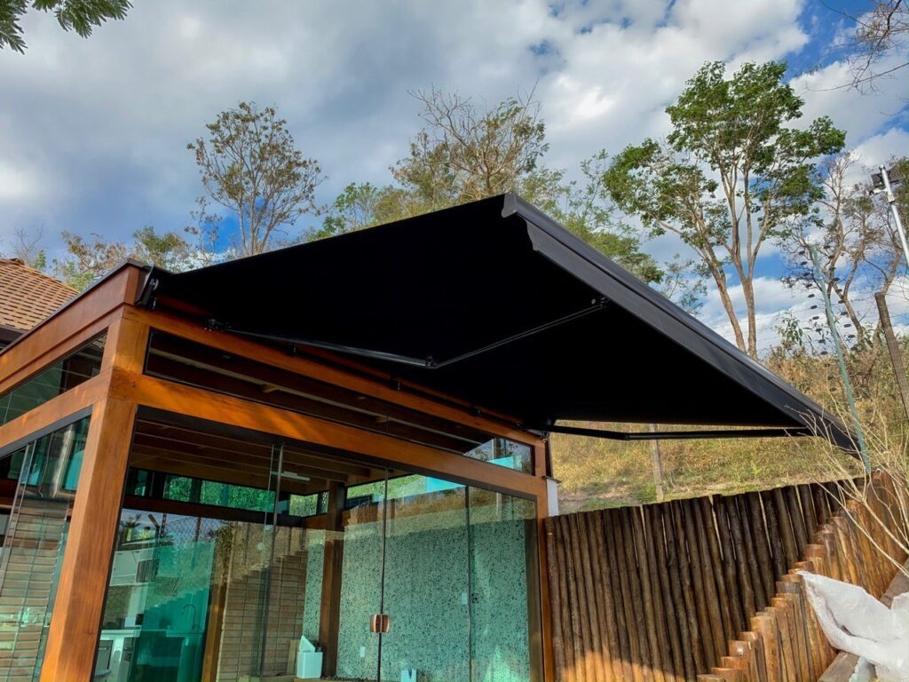 Toldo articulado em casa com fachada de vidro